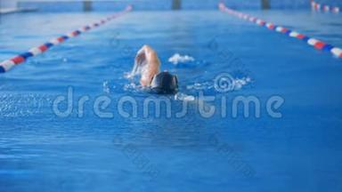 一个女运动员用每只手臂<strong>依次</strong>在游泳池里游泳。