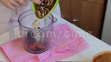 自制糖果放在盘子里。 旁边的食材为他们准备.. 女人把坚果扔进搅拌机里。