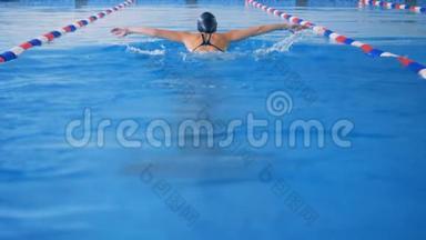 游泳运动员以完美的蝴蝶风格<strong>远离</strong>相机。