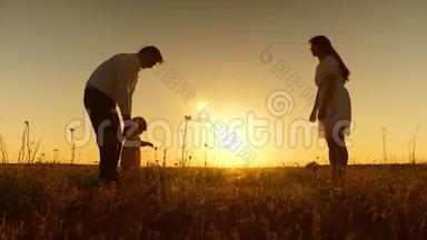 年轻的父母教孩子在金色的夕阳下用脚<strong>走路</strong>。