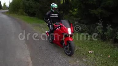 一个骑摩托车的人。 年轻的帅哥骑摩托车在山路上。 他坐在摩托车上
