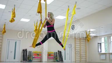 <strong>年轻</strong>美丽的<strong>瑜伽女子</strong>在健身俱乐部的紫色吊床上做空中<strong>瑜伽练习</strong>