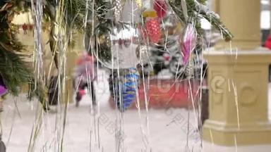 用球和玩具装饰的圣诞树。 她站在街上，下雪了。 在背景中，节日