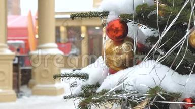 用球和玩具装饰的圣诞树。 她站在街上，下雪了。 在背景中，节日