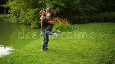 健康强壮的男<strong>朋友</strong>在市立公园拥抱并在户外旋转他的女<strong>朋友</strong>。可爱的一对享受夏天