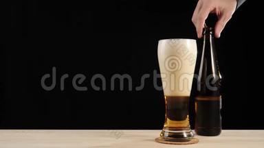新鲜啤酒。 啤酒杯杯中的美味工艺啤酒放在黑色背景下的木桌上。 带水的冷鲜啤酒