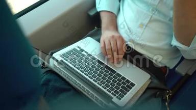 商务人员在乘坐火车时用手拿笔记本电脑，俯视图