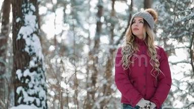 年轻微笑的女人享受冬天。 女人穿着温暖的衣服在寒冷的冬天的雪林里。 拍摄红色史诗