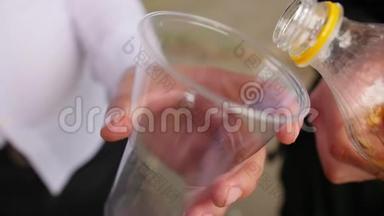 把柠檬水从瓶子里倒入塑料玻璃里。 近距离射击。