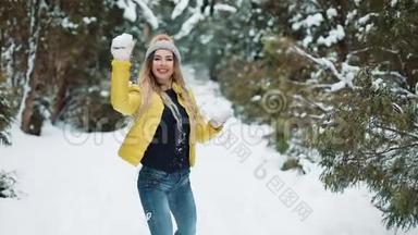 可爱的女孩在森林里玩雪球。活跃的年轻女子在镜头前玩雪球
