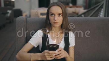 一个拿着一杯酒的单身女人抬头看着镜头。 绝望女孩
