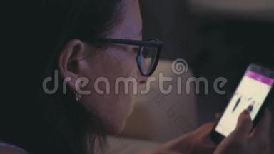 一位戴眼镜的女士坐在沙发上，用智能手机进行<strong>网上</strong>购物。 <strong>网上</strong>营销