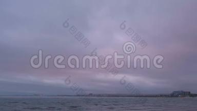 薄雾和雾气笼罩着海面.. 美丽的海景与粉红色日落和沿海城镇。