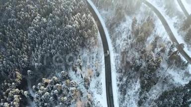 头顶高空俯视汽车行驶在簪弯转弯的山路上，冬雪覆盖森林。 白色