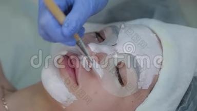 专业美容师女士用脸刷向客户敷面膜。