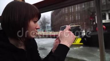 女孩乘船穿过阿姆斯特丹的运河，在电话里拍照