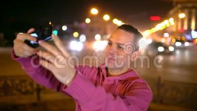 智能手机自拍-有吸引力的西班牙裔男人使用智能手机相机拍摄自我肖像。 年轻人在自拍