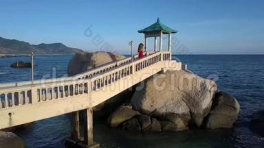 在岩石之间的石桥上的一个蔚蓝的海景女孩