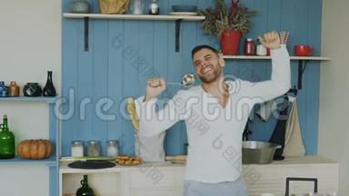在家厨房做饭的时候，一个英俊的年轻滑稽男子用勺子跳舞唱歌