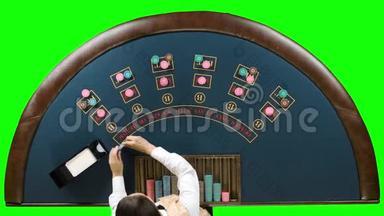 <strong>扑克</strong>桌上的商人把筹码放在<strong>扑克</strong>游戏下面。 绿色屏幕。 顶部视图