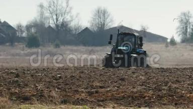 拖拉机蓝色的大黑色车轮和强大的轮，<strong>沉</strong>重的犁，黑<strong>暗</strong>肥沃的土壤。 农业