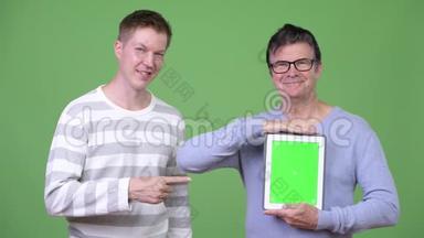 高级帅哥和年轻帅哥一起展示数码平板电脑