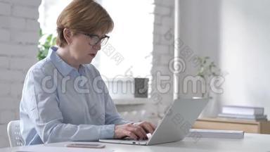失落、沮丧的老妇人在笔记本电脑上工作