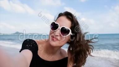可爱的长发女孩在日落的沙滩上用手机或相机自拍照片享受大自然