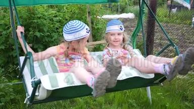 两个女孩姐妹在荡秋千。 娱乐和户外娱乐活动.. 夏日。