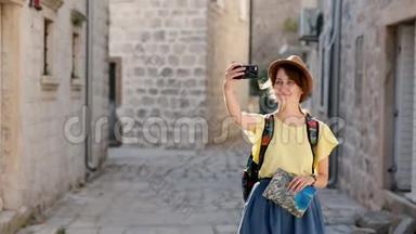 开朗的女游客戴着帽子，在现代手机设备上拍一张照片走在街上。 积极的潮人