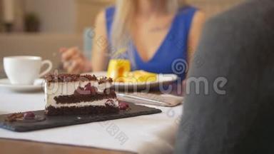 女人面前的一块甜蛋糕在咖啡馆里试着吃甜点