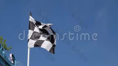 格子的赛车旗在蓝天背景下在空中摇动。