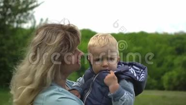 快乐的年轻金发母亲抱着她的孩子在公园散步