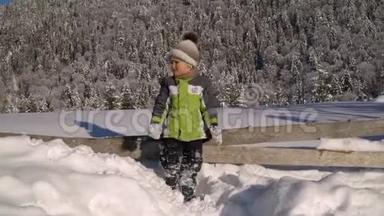 冬天，小可爱的男孩在外面的雪地里玩耍。 背景是一片雪林.. 这个男孩很高兴。