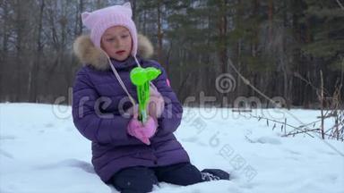 冬天森林里坐在雪地里堆雪人的女孩