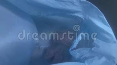塑料污染，一个废弃的塑料袋在蓝色的水里漂浮着水母。 水母被困在塑料袋里。