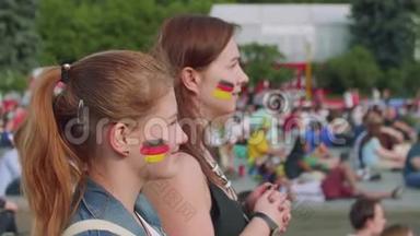 在球迷区的足球赛中，女孩为德国队加油