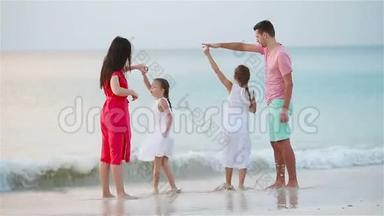 父母和可爱的两个孩子在海滩上的暑假里玩得很开心。 四口<strong>之家</strong>相爱，<strong>幸福</strong>