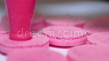 美味可口的法式甜点。 制作粉红色的马卡龙，从糕点中挤压和添加奶油馅