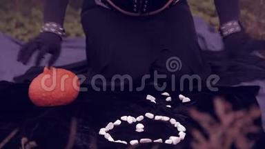 一个穿着黑色衣服的女巫召唤着白色的石头。 万圣节。