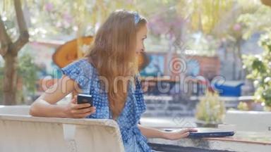 坐在长凳上的蓝衣少女将笔记本电脑夹在<strong>桌面上</strong>
