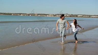 海滩暑假夫妇在假期跑步。 快乐的海滩度假情侣一起笑着玩