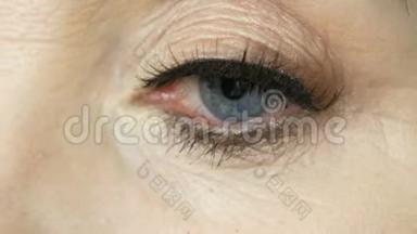 专业<strong>化妆</strong>师把假睫毛贴在一个成<strong>年中</strong>年妇女的蓝色眼睛上，近距离观看