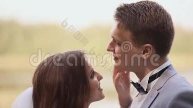 年轻夫妇新郎和新娘一起在大自然中。 他们互相看着。 傻瓜。 接吻。 一起快乐。 结婚纪念日。