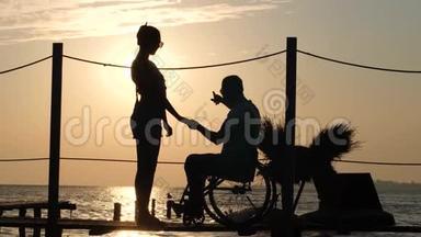 残男的剪影与心爱的女子在海上码头的傍晚余晖在橘色的天空和水的背景下