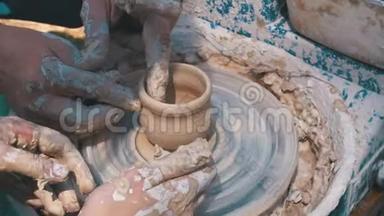 陶工的手和陶工`车轮上的陶土花瓶