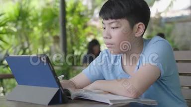 可爱的亚洲男孩使用平板电脑，年轻的十几岁男孩在数字平板电脑上做作业，默默面对。