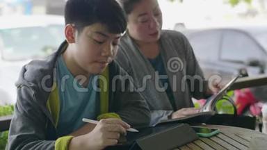 亚洲男孩玩平板<strong>电脑</strong>，和他的母亲交谈，微笑着<strong>面对</strong>。