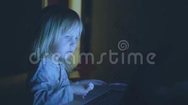 小孩子在家里一个黑暗的房间里玩电脑。