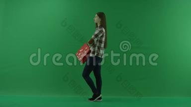 女孩站在她的左边，把她的袋子放在她弯曲的胳膊肘上，等待绿色屏幕上的东西